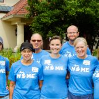 Alumni pose in front of the Alumni House